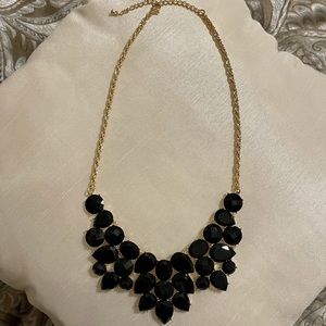 Chunky black necklace with a gold colored clasp chain